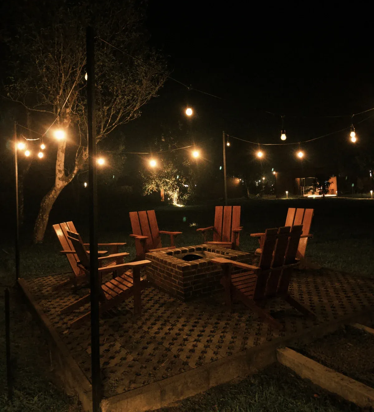 Outdoor patio with wooden chairs and string lights glowing at night