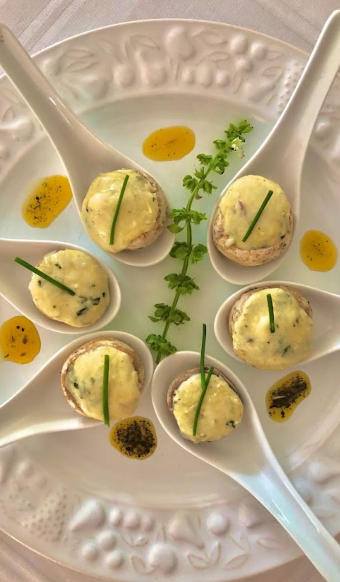 Um prato branco coberto com colheres cheias de comida.-Pousada-Recanto-do-Chef