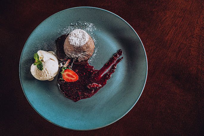 Um prato de comida com sorvete e um morango em cima da mesa.-Pousada-Recanto-do-Chef