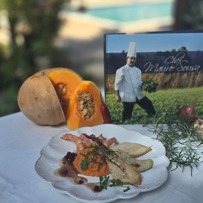 Um prato de comida está sobre uma mesa em frente ao livro de um chef-Pousada-Recanto-do-Chef