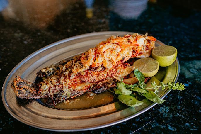 Um prato de comida com um peixe e um camarão sobre uma mesa.-Pousada-Recanto-do-Chef