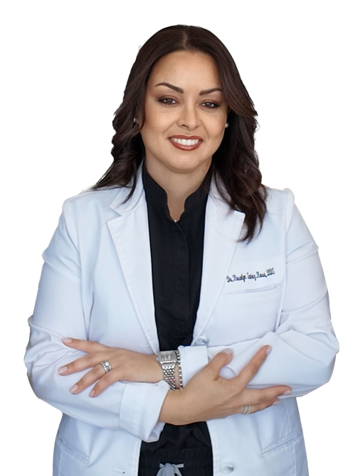 A woman in a white lab coat is smiling with her arms crossed