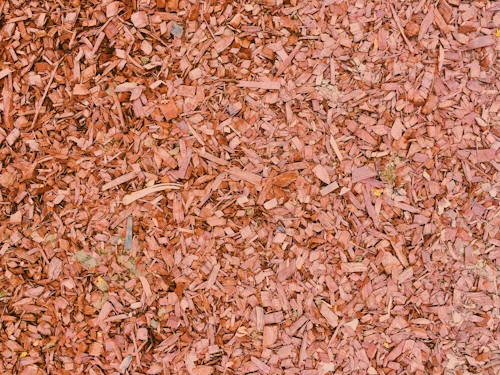 A pile of red mulch is sitting on the ground.
