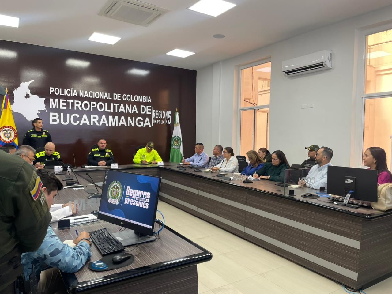 Un grupo de agentes de policía y civiles sentados alrededor de una gran mesa de conferencias