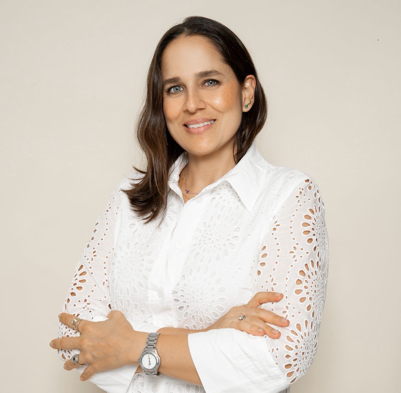 Una persona sonriente, de cabello oscuro, que viste una camisa blanca 
