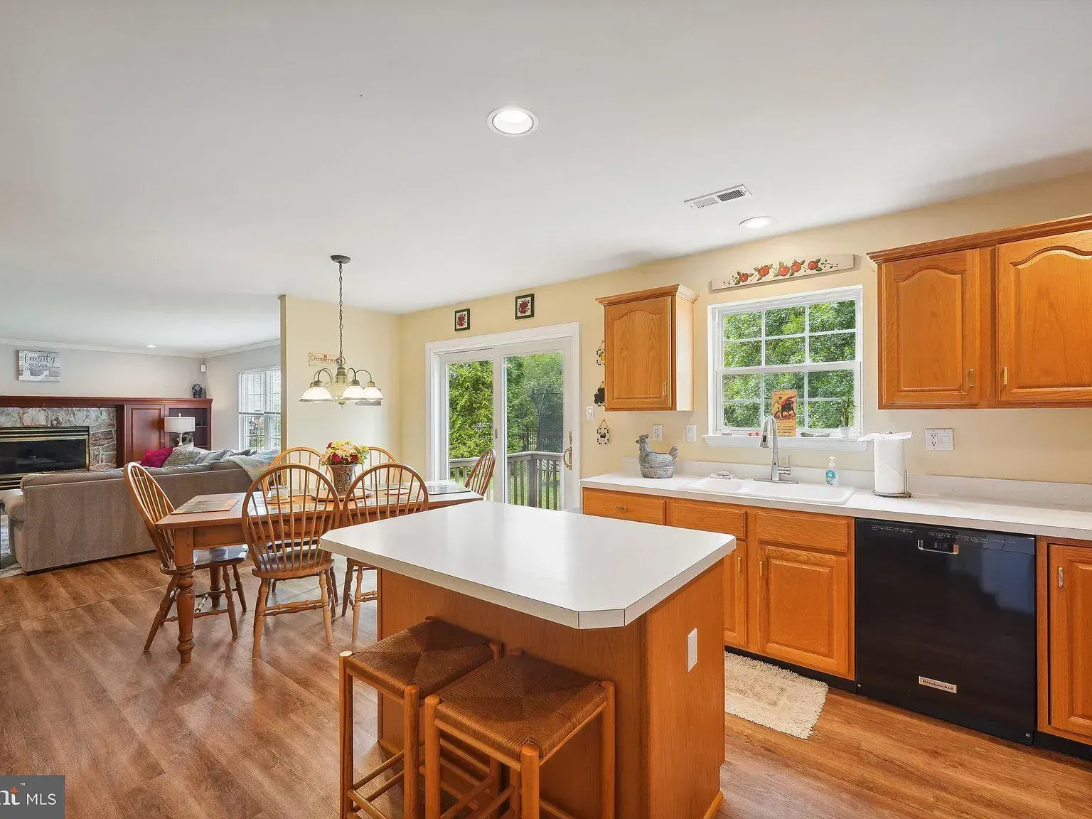 Bright kitchen with wood cabinets, white island, dining table, and large windows overlooking a patio