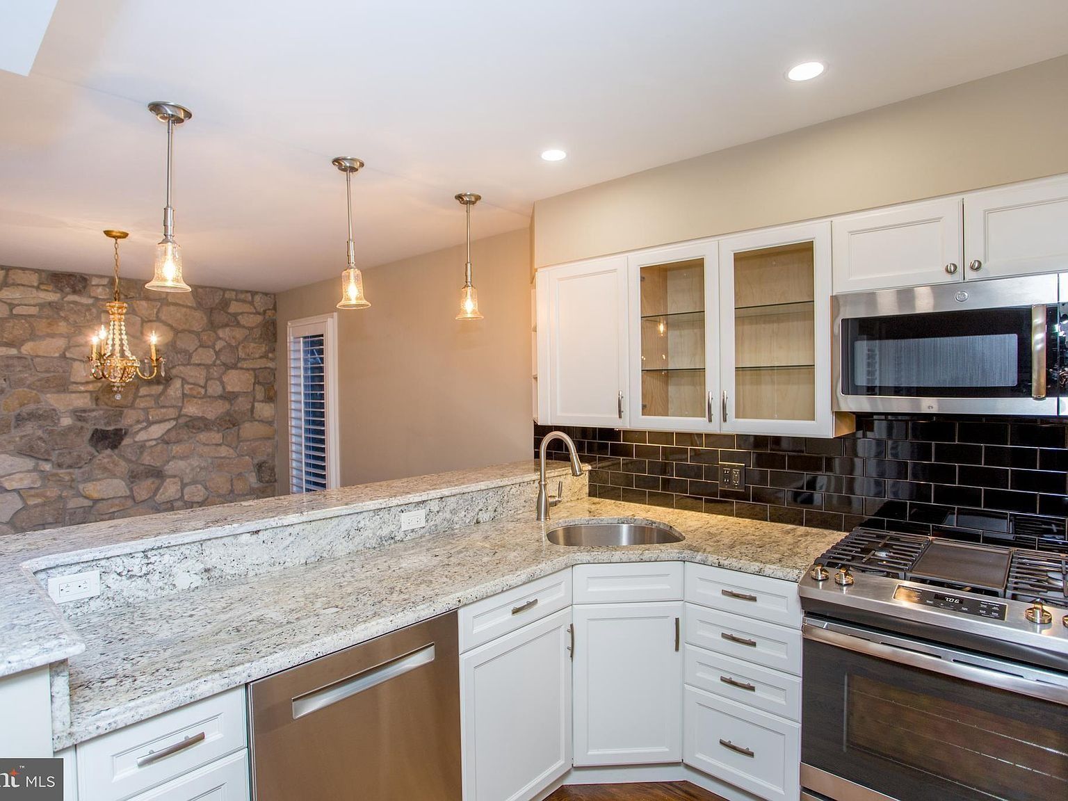 Modern kitchen with white cabinets, granite counters, black tile backsplash, and stainless steel appliances