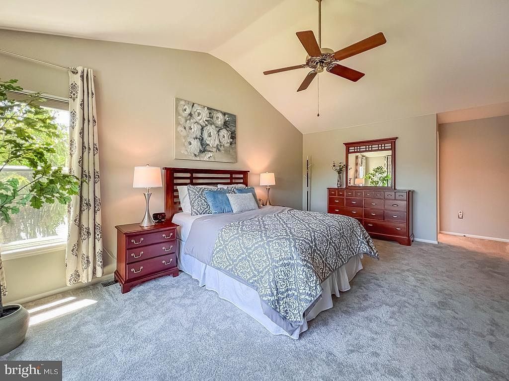 Bright bedroom with a large bed, red nightstands, and a ceiling fan, lit by daylight from a window.