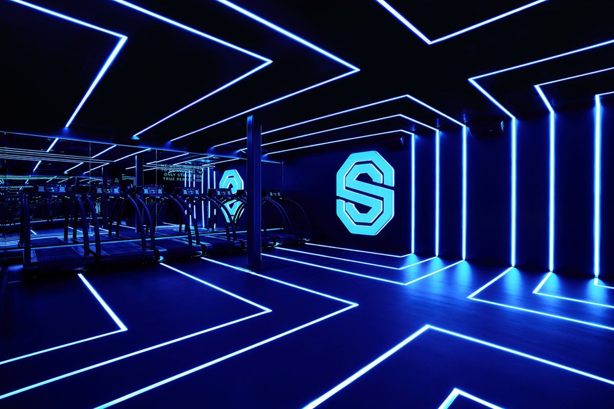 Neonblauw futuristisch interieur met lichtgevende geometrische lijnen en een verlichte logowand in een donkere ruimte