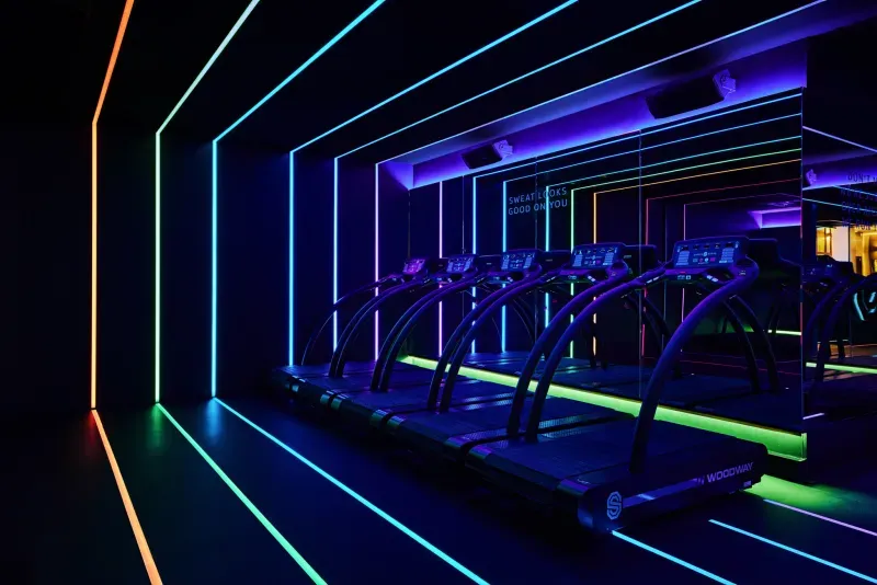 Met neon verlichte sportschool, rijen loopbanden die oplichten en paarsblauwe sfeerverlichting