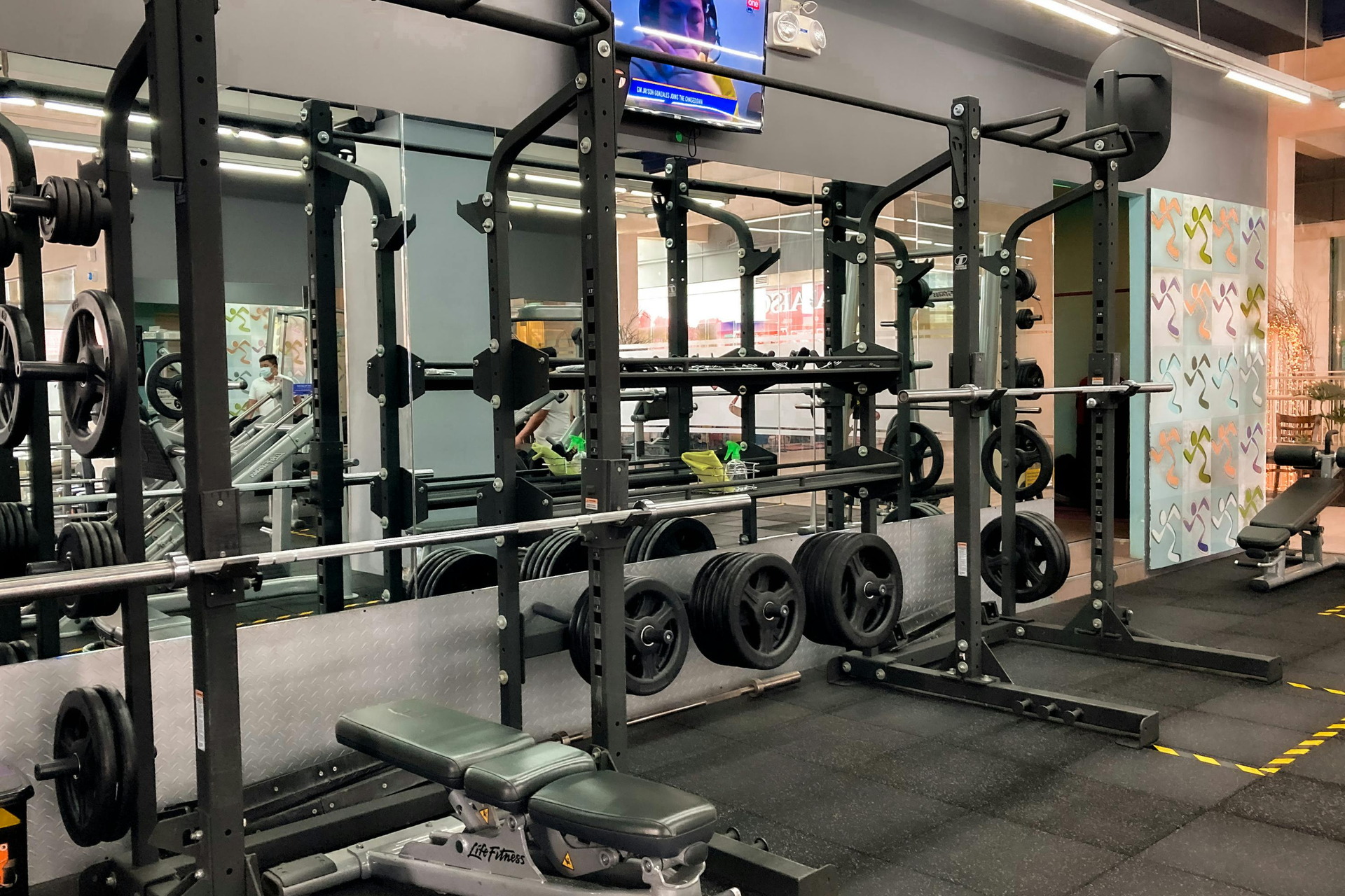 Moderne sportschool met squatrekken, halters, spiegels en halterschijven op een zwarte rubberen vloer.