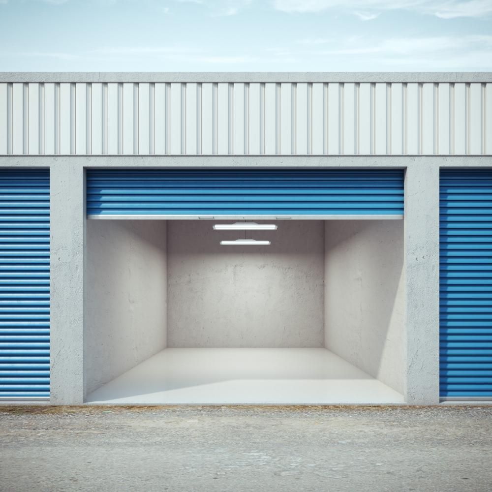 An Empty Garage With Blue Doors And A White Building — Raymond Terrace Public Storage In Heatherbrae, NSW