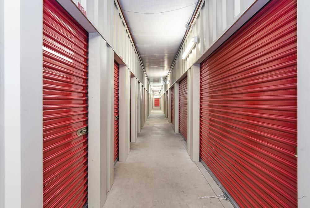 A Long Hallway With Red Doors In A Storage Facility — Raymond Terrace Public Storage In Karuah, NSW