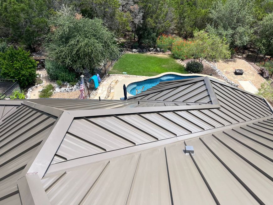 Metal roof with a view of a pool and greenery. Brown roof, turquoise pool, and green landscape.