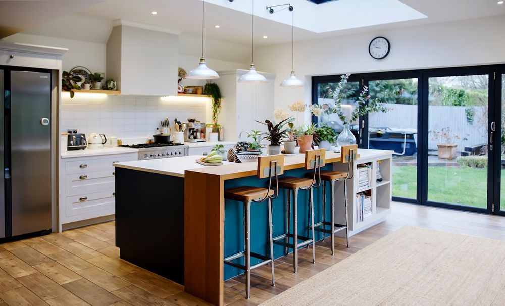 A kitchen with a large island and stools and a large window.
