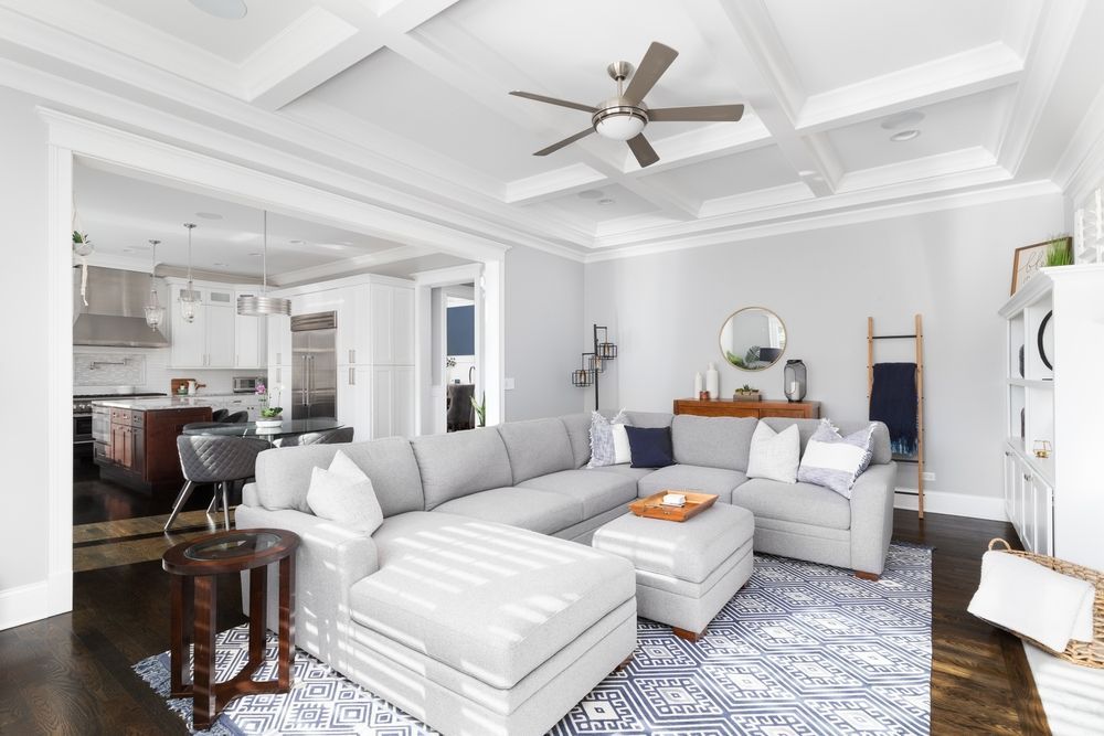 A living room with a large sectional couch and a ceiling fan.