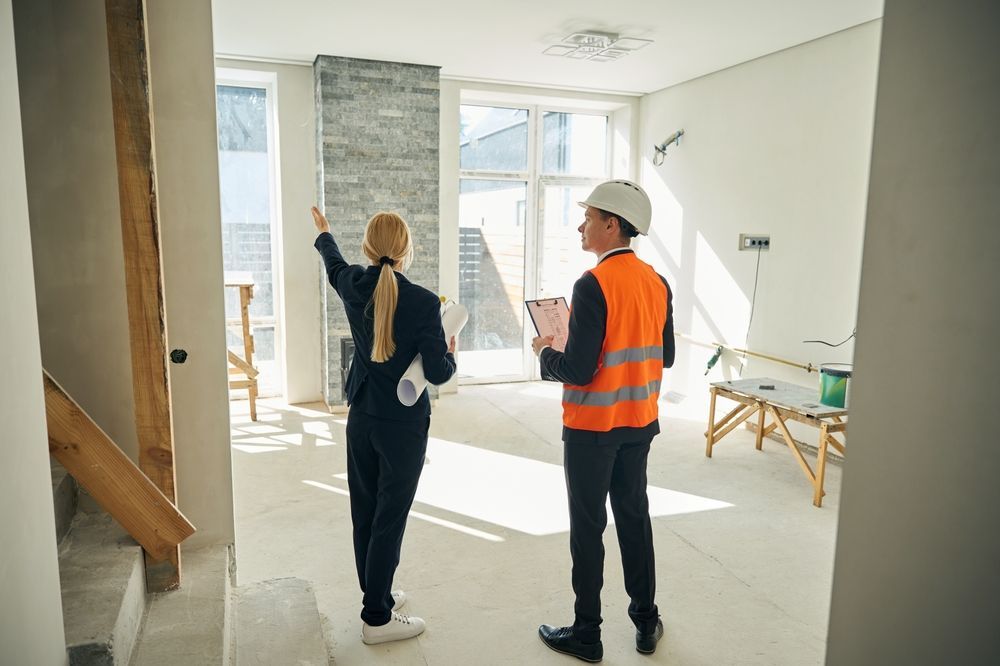 A man and a woman are standing in a room in a house under construction.