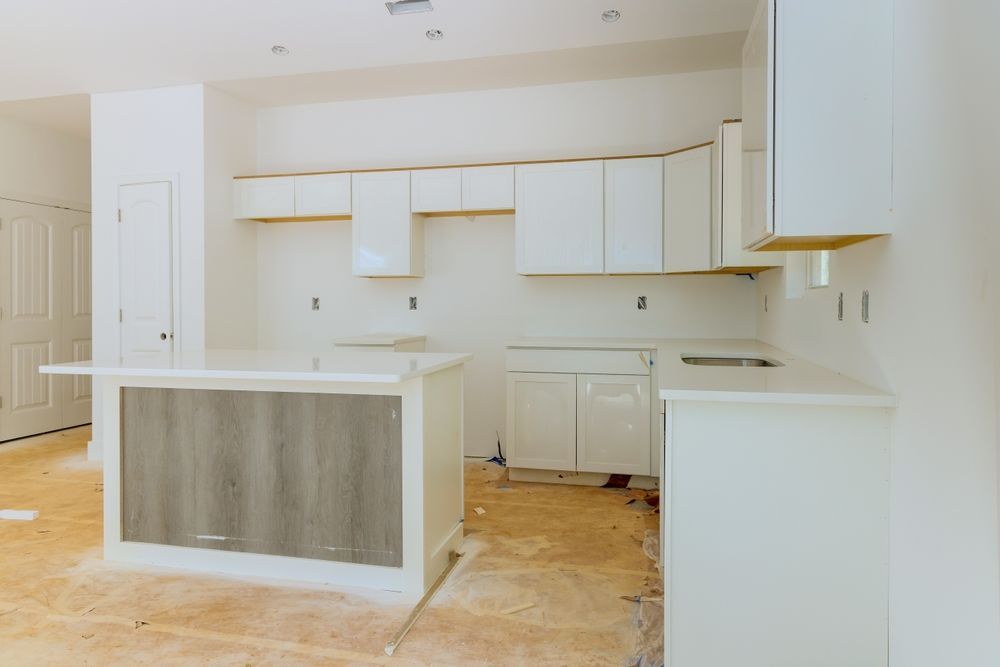 A kitchen under construction with white cabinets and a wooden island.