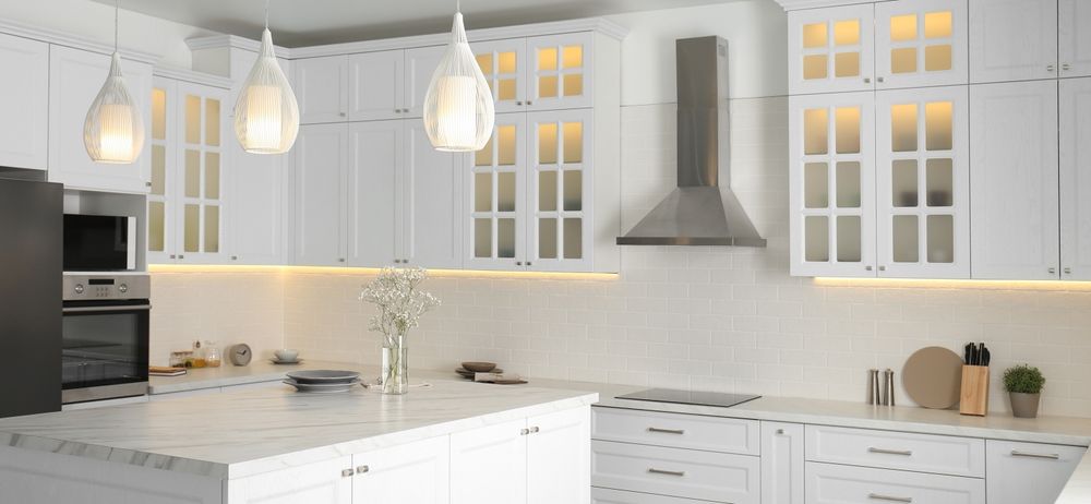 A kitchen with white cabinets and a large island in the middle.