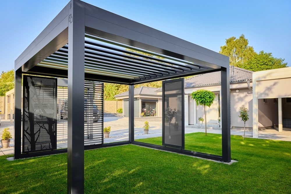 A pergola is sitting on top of a lush green lawn in front of a house.