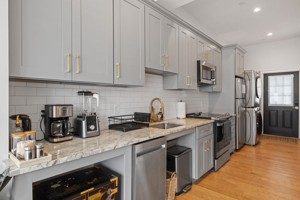 A kitchen with stainless steel appliances and gray cabinets.