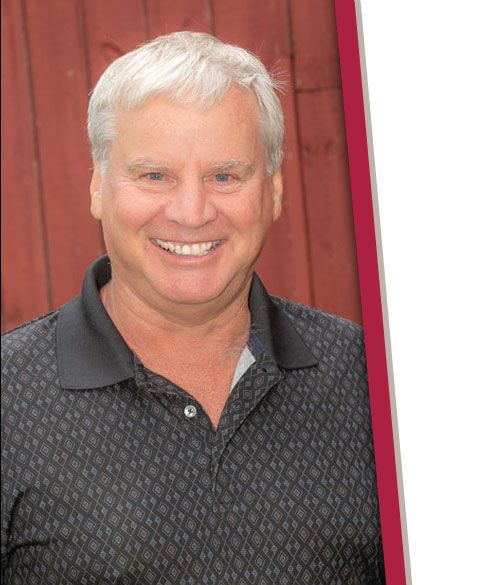 A man in a black shirt is smiling in front of a red wall