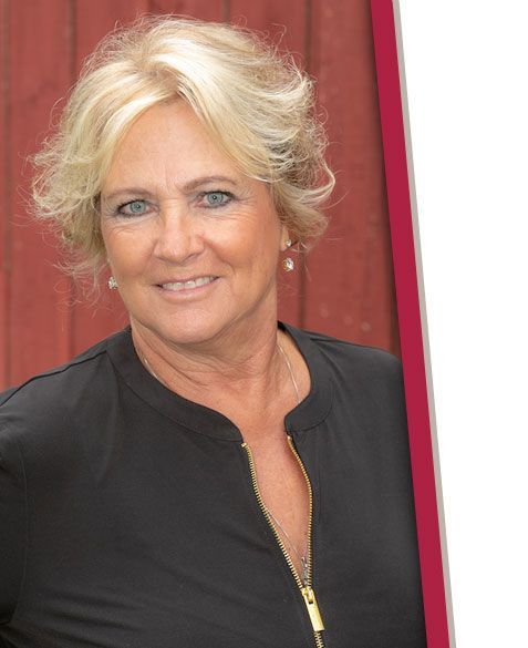 A woman in a black shirt is smiling in front of a red wall.