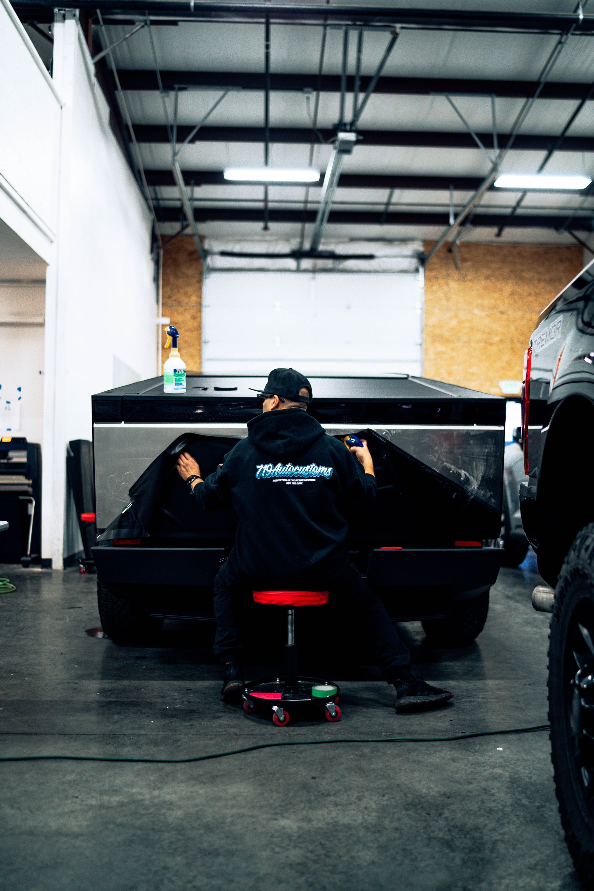 Mechanic working on a black car inside an auto shop garage