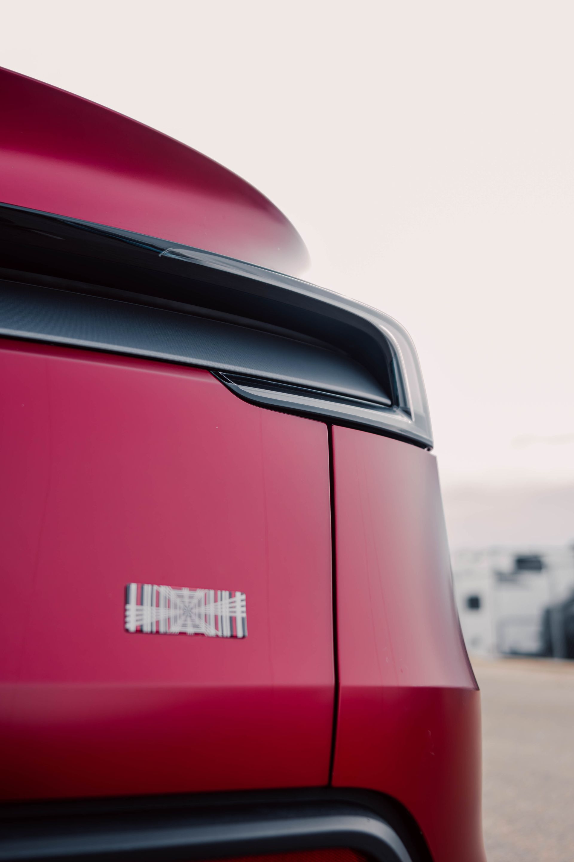 Close-up of the rear of a red car with a black taillight strip and badge.