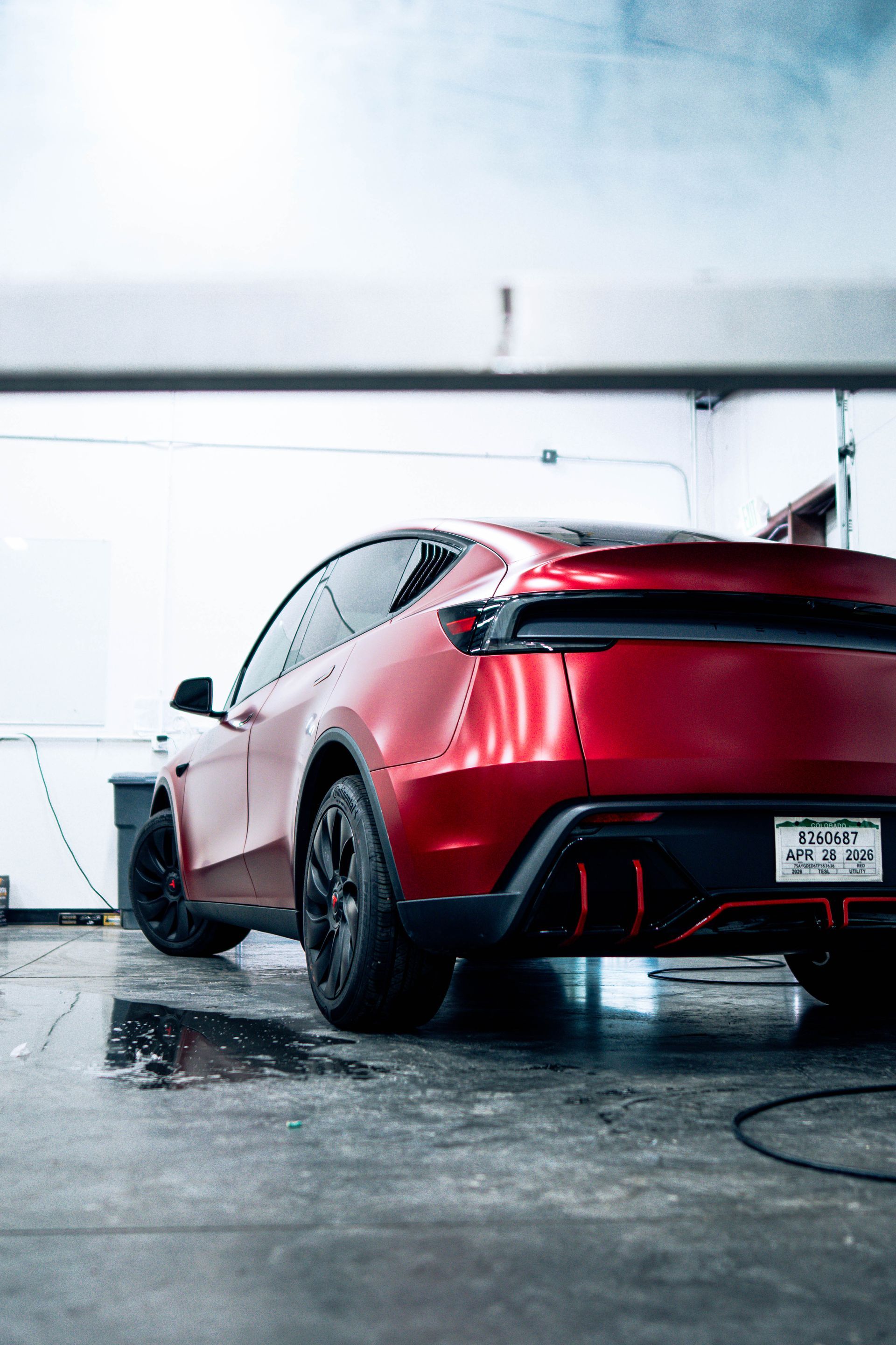Red sports car in a garage, rear view on a wet floor with dramatic lighting