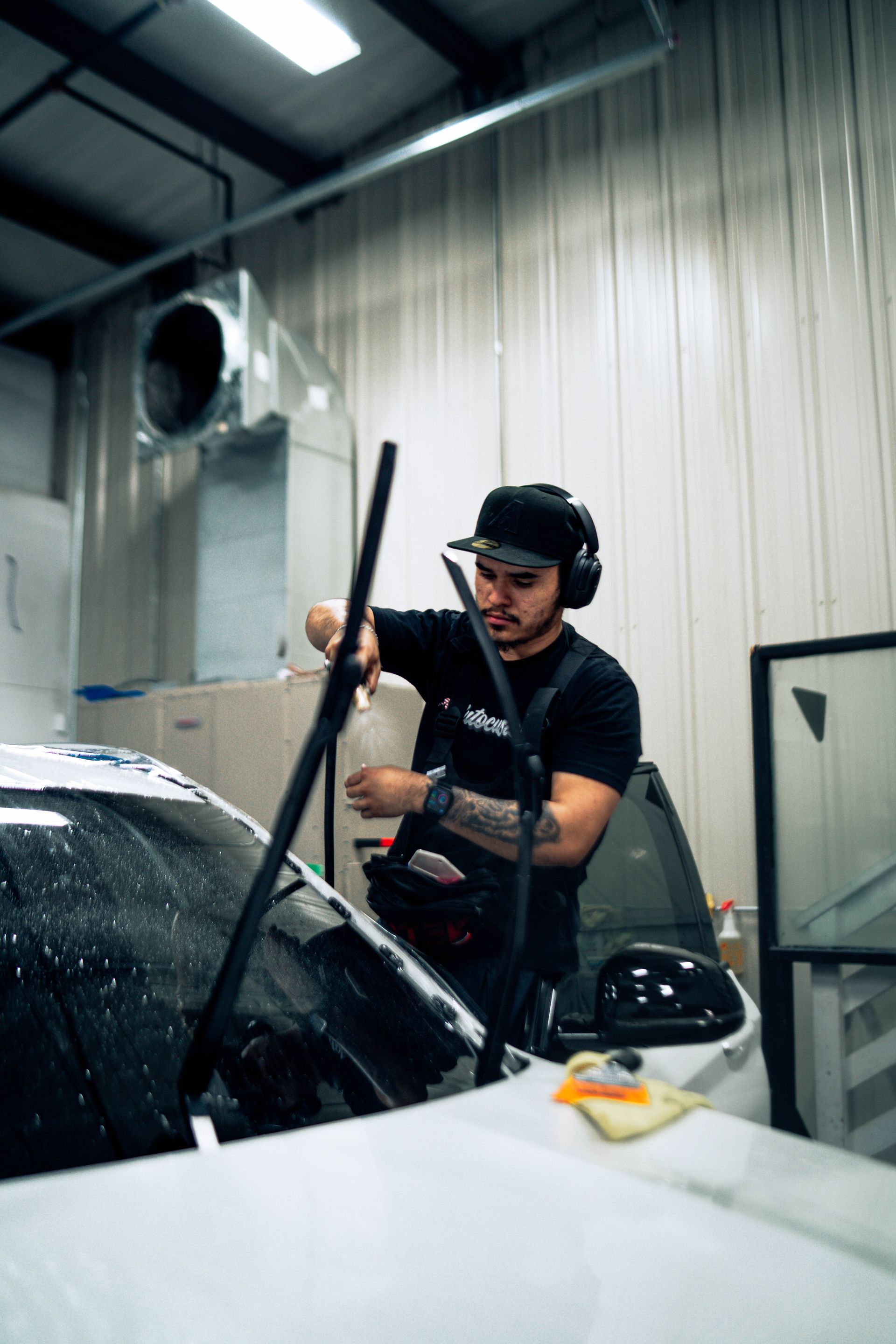 Person washing a white car with a squeegee in an indoor auto wash bay