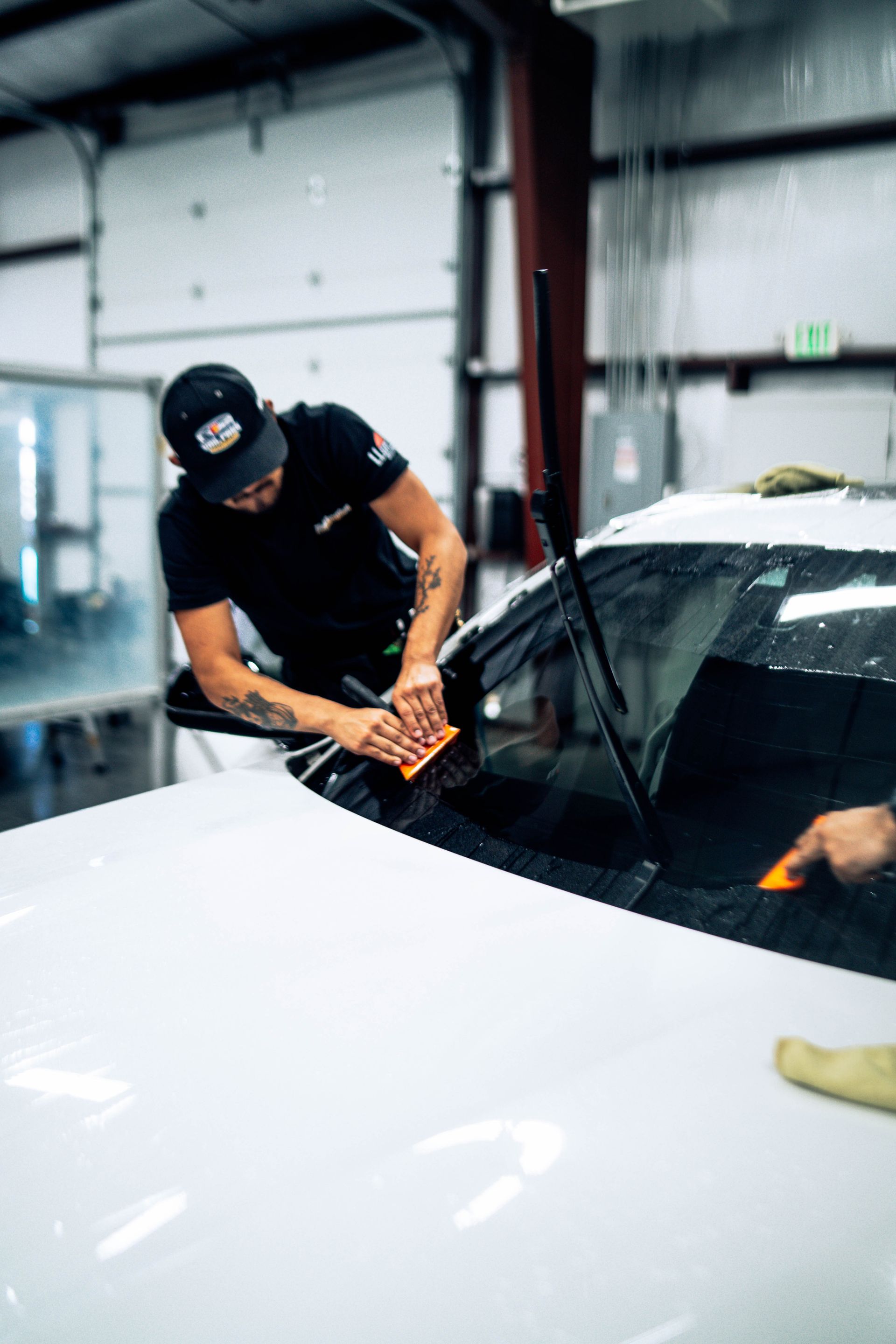 Technician removing a windshield from a white car in an auto repair shop