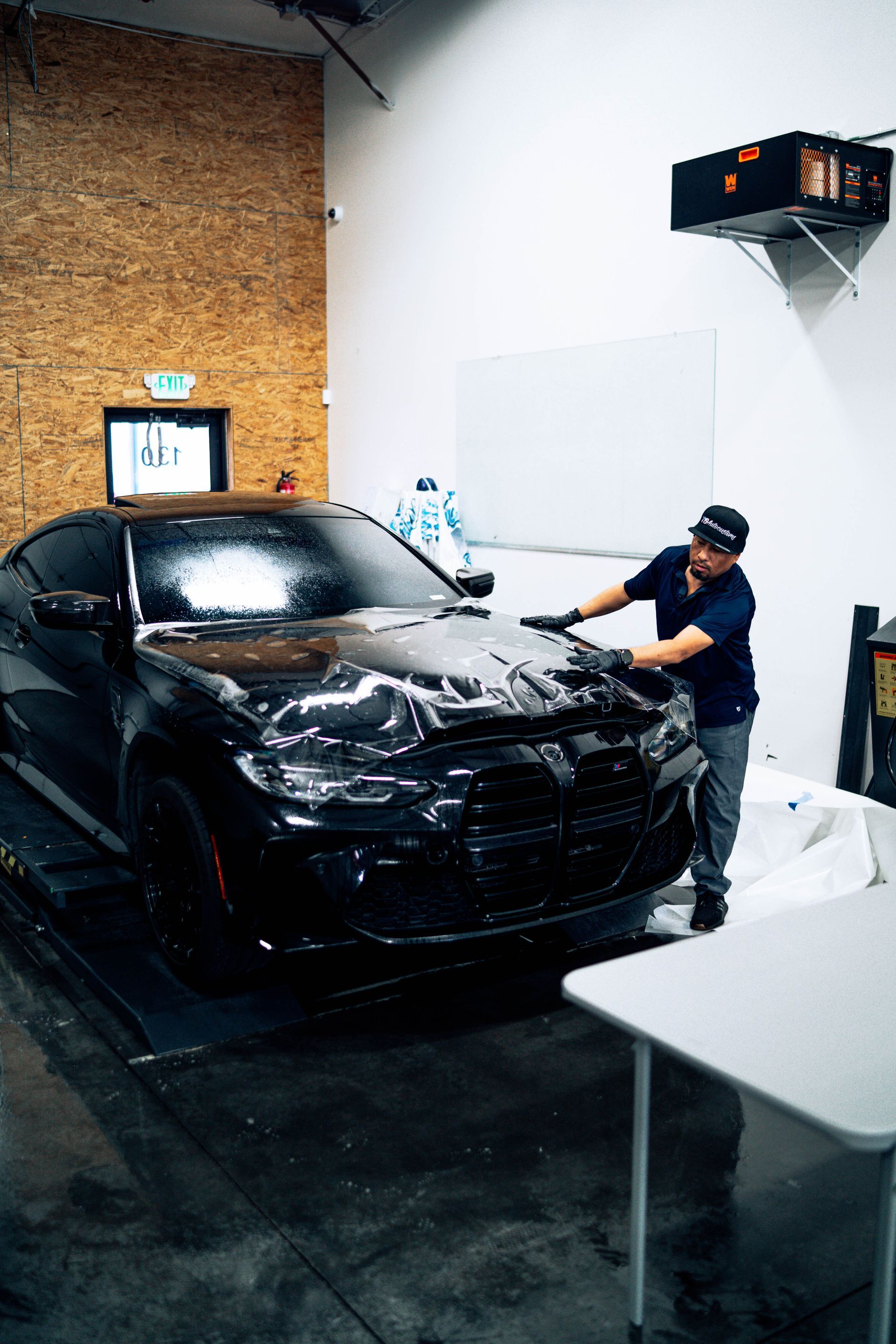 Person washing a black car in an indoor garage or detailing bay
