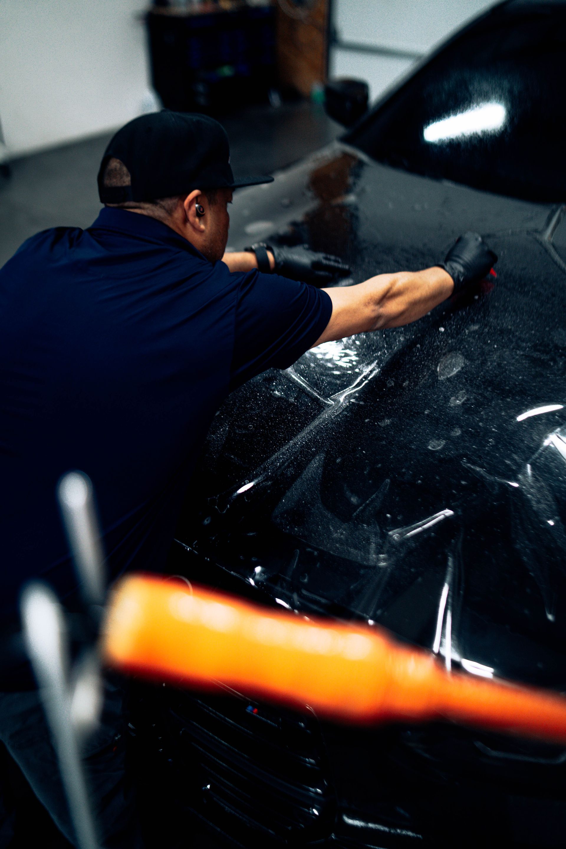 Installer working film onto a black vehicle