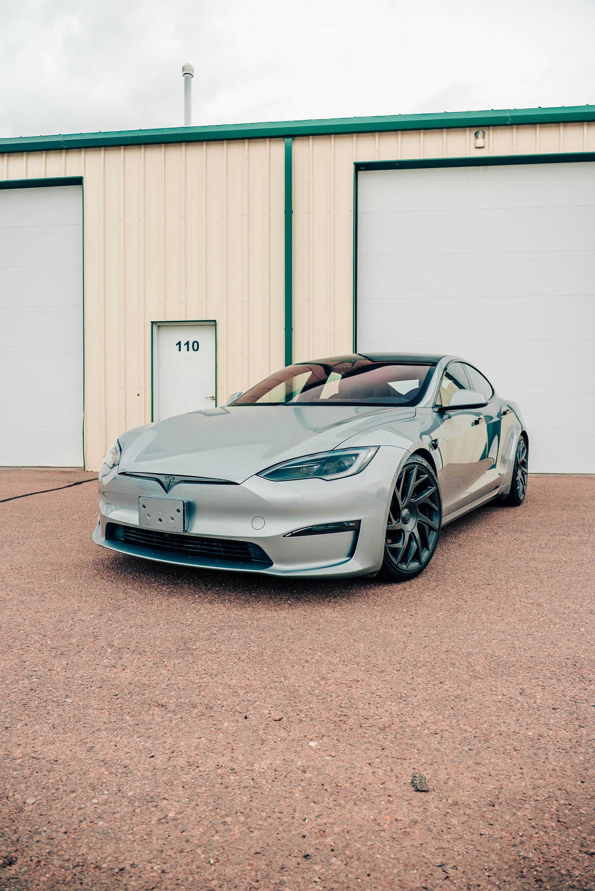 Silver sports sedan parked in front of a beige garage building