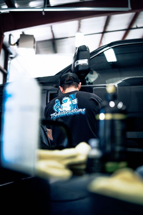 Mechanic working under a lifted car in a garage, with tools and equipment in the foreground