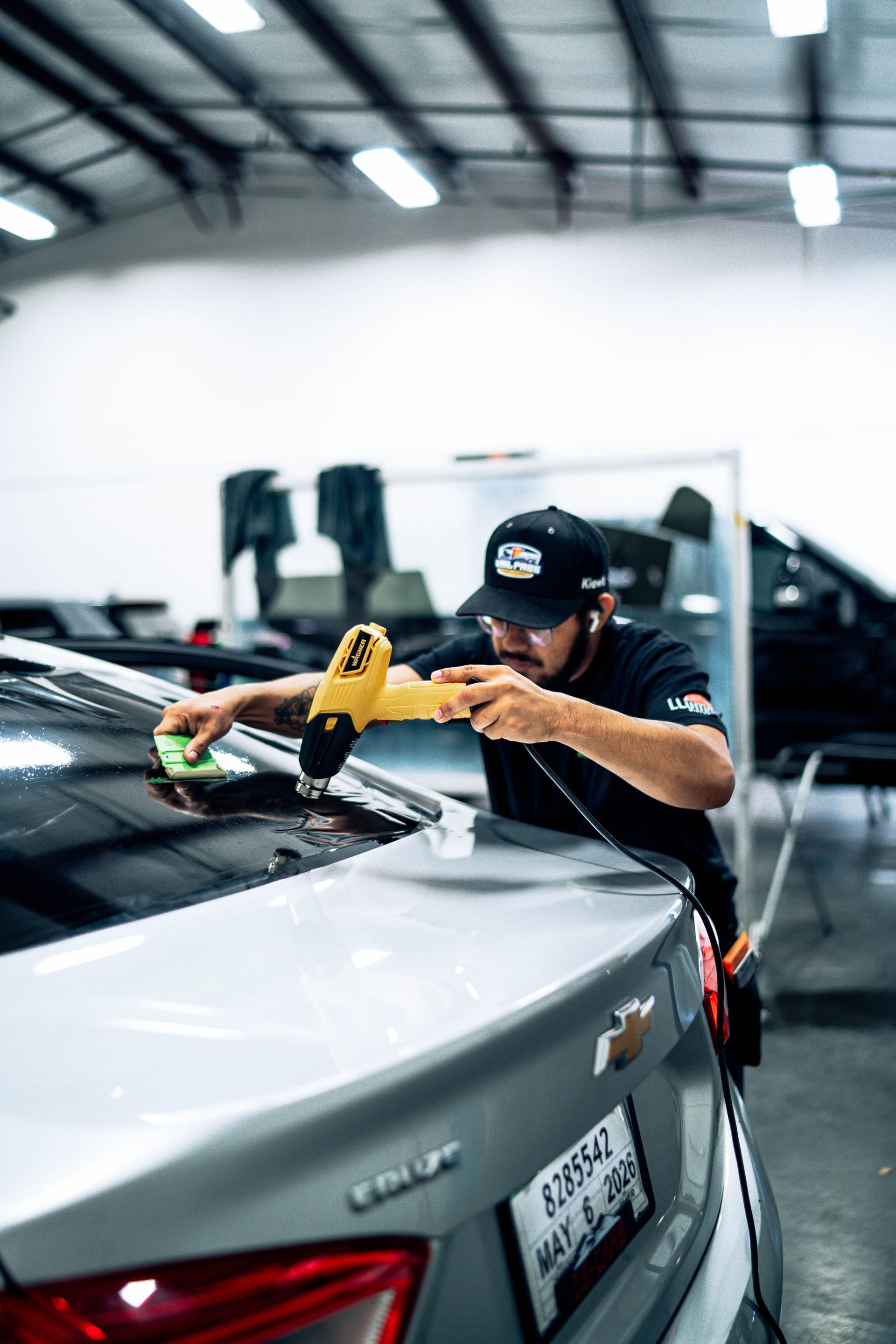 Technician polishing a silver car with a buffer in a workshop