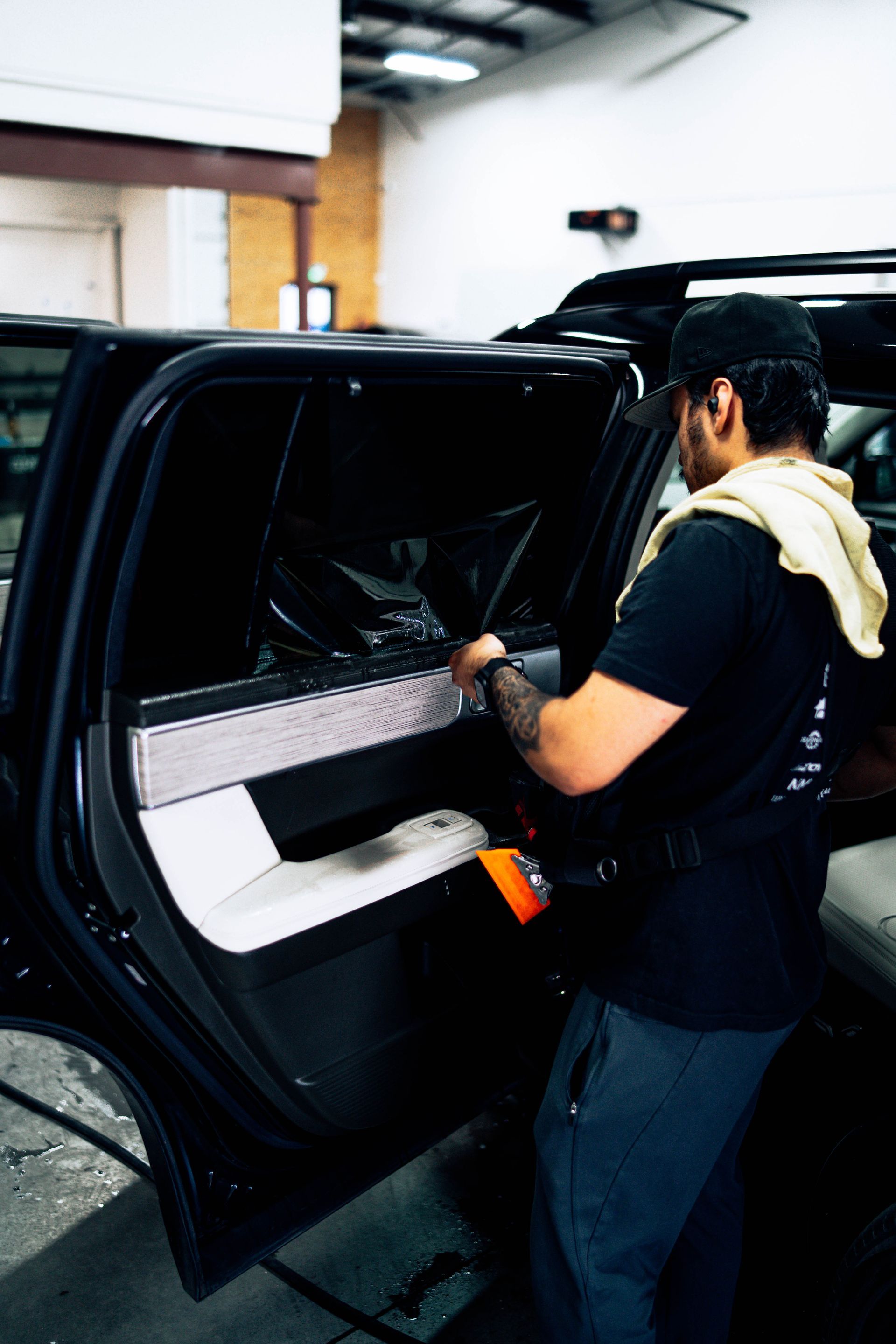 Mechanic working inside a black car door in a garage