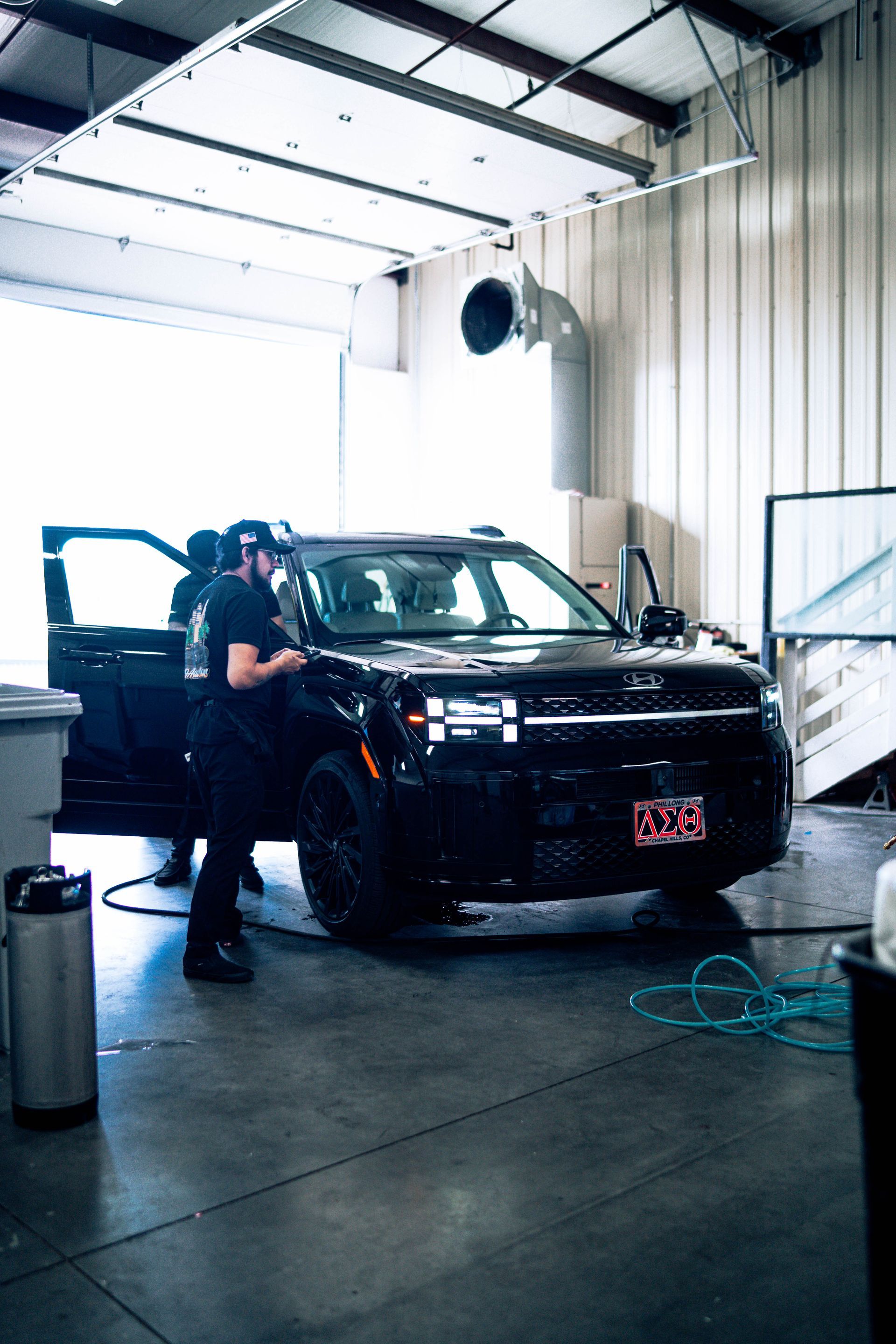 Mechanic inspecting a black SUV inside a garage, with tools and wet floor nearby