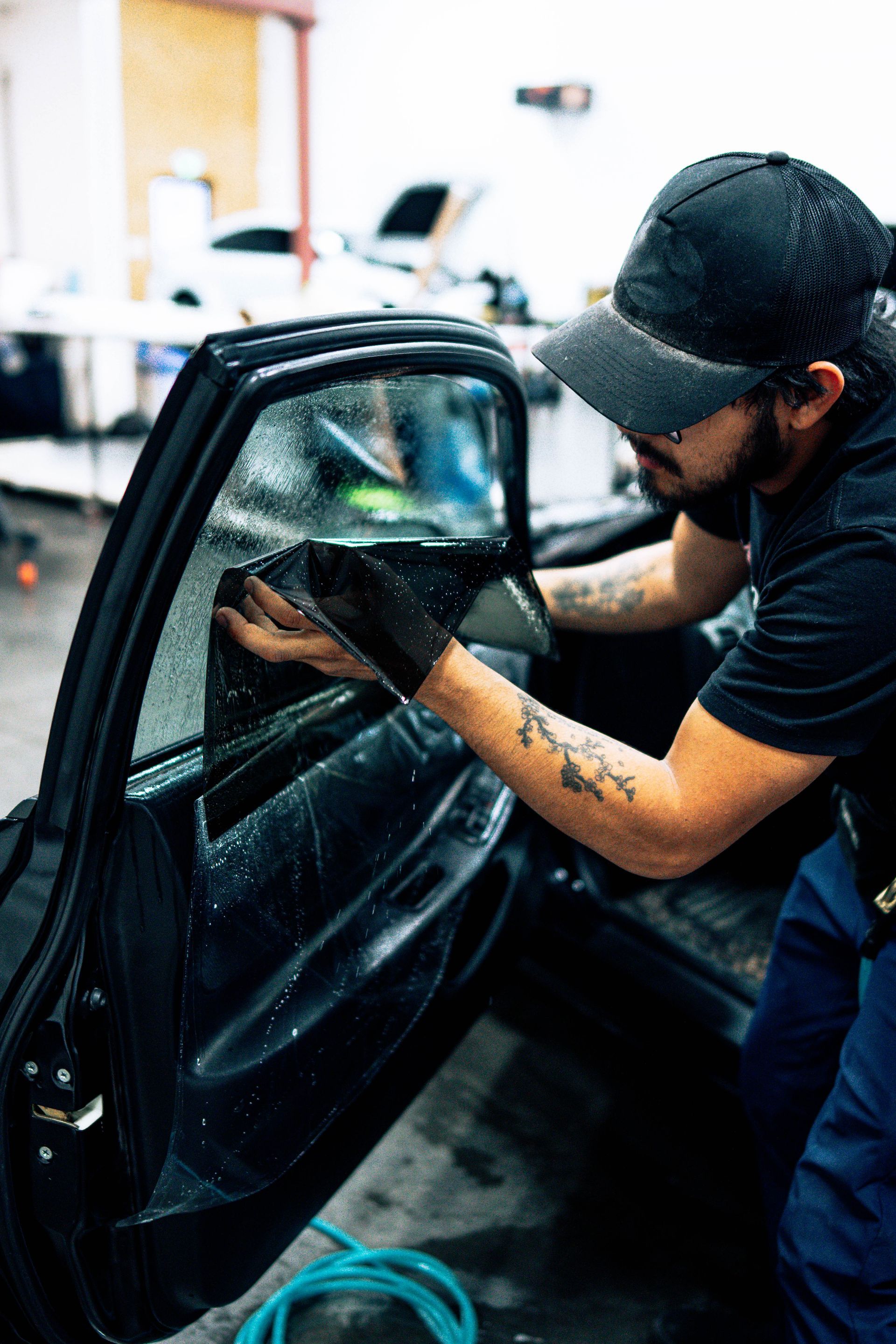 Person cleaning a black car door in a workshop