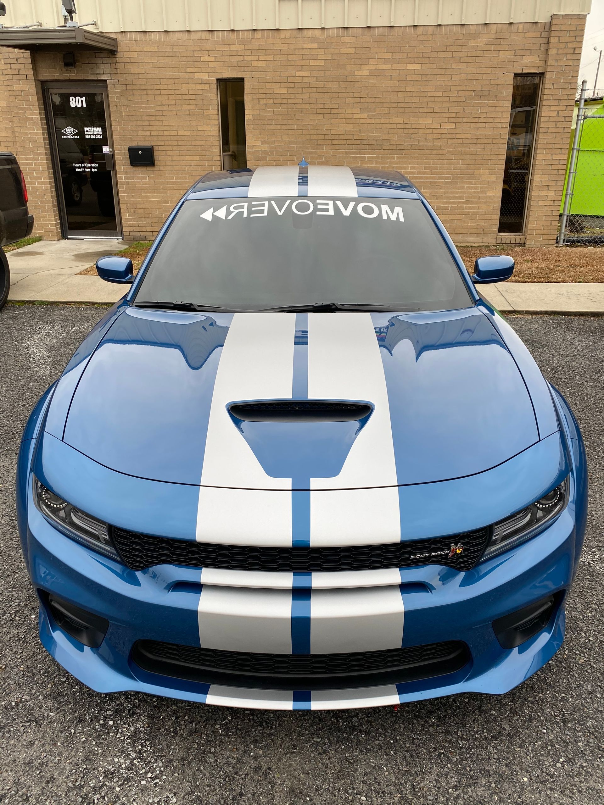 A bright blue Dodge Charger with silver racing stripes and a