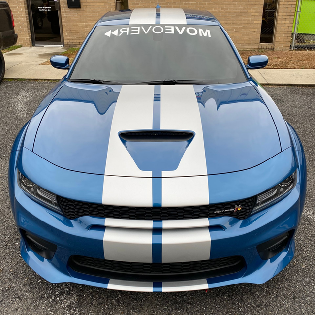 A blue Dodge Charger with white racing stripes and a