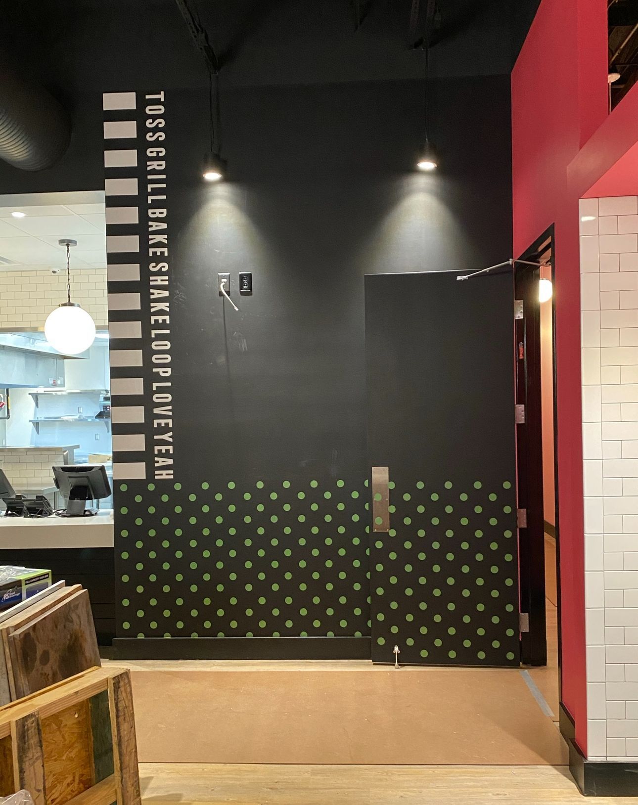 A black wall in a restaurant featuring a vertical list of words and a green polka-dot pattern on the lower section.