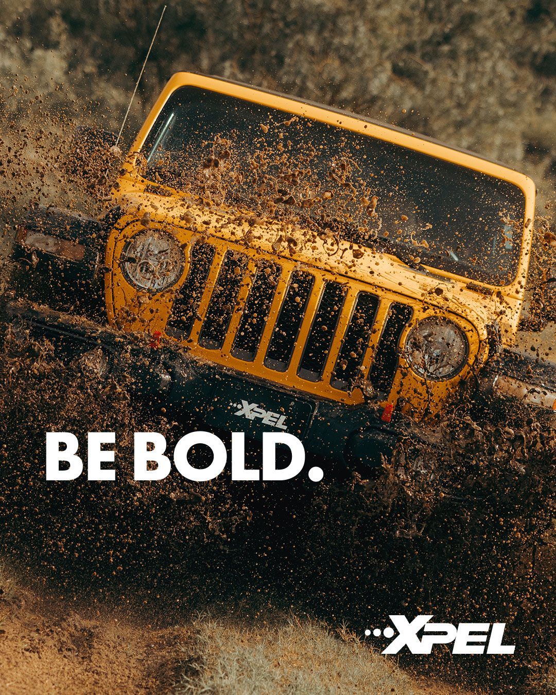 A bright yellow Jeep drives through mud, splattering it everywhere. Text reads 