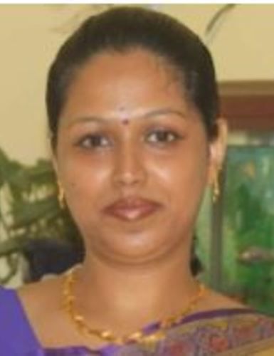 Portrait of a woman wearing a purple sari and gold necklace, facing the camera with a slight smile.