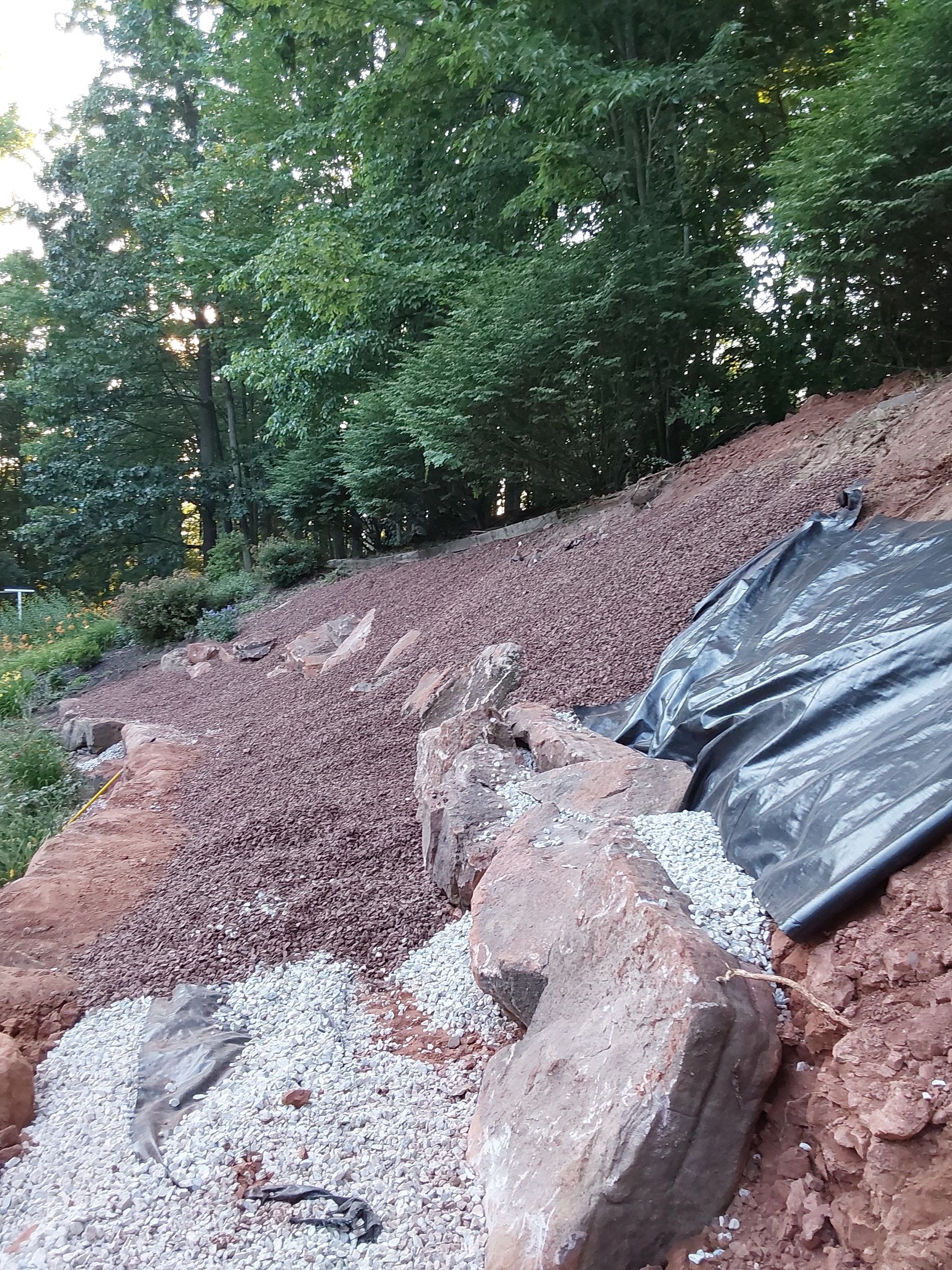 a pile of rocks and gravel on top of a hill with trees in the background