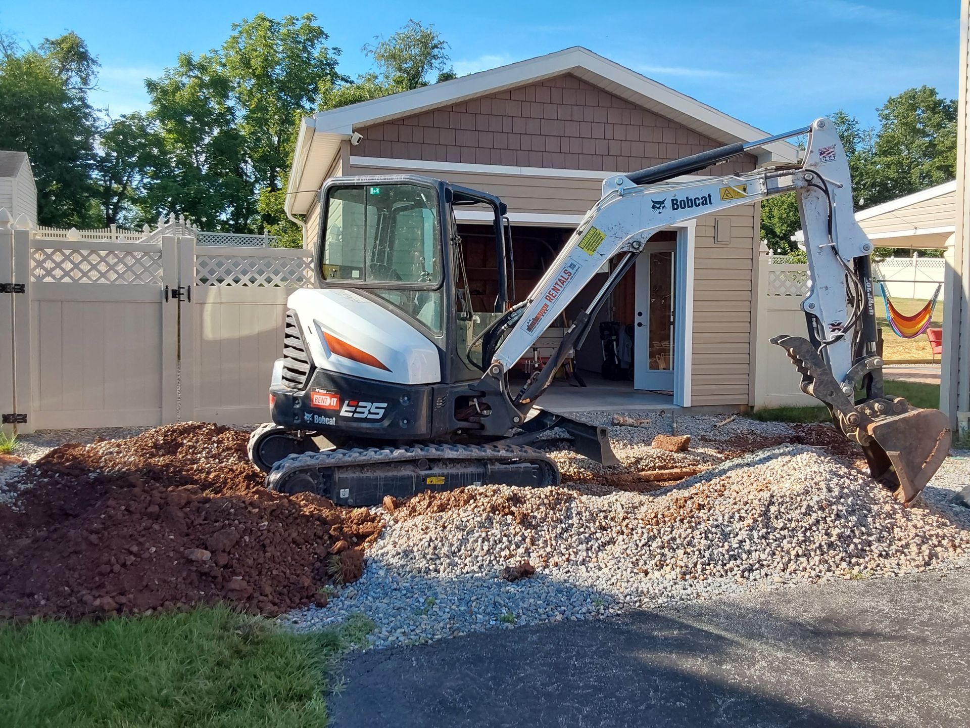 a small excavator is digging a hole in front of a house