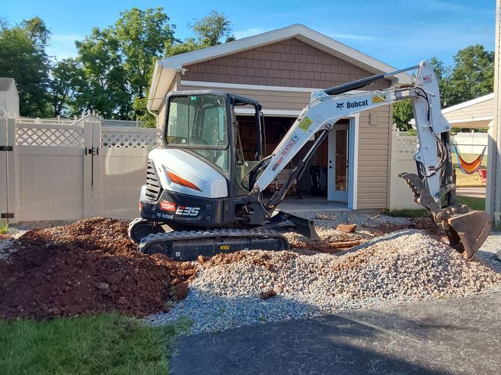 a small excavator is digging a hole in front of a house