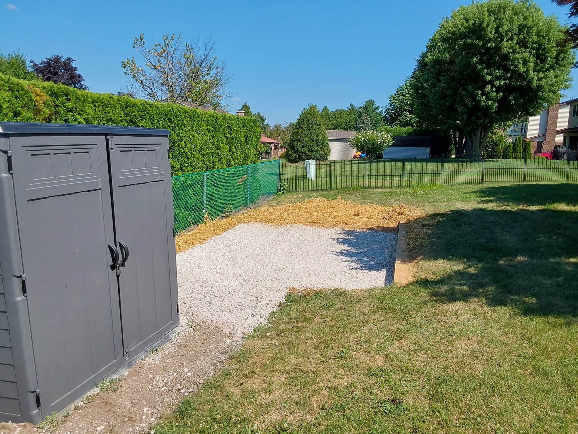 a gray shed is in the middle of a grassy yard