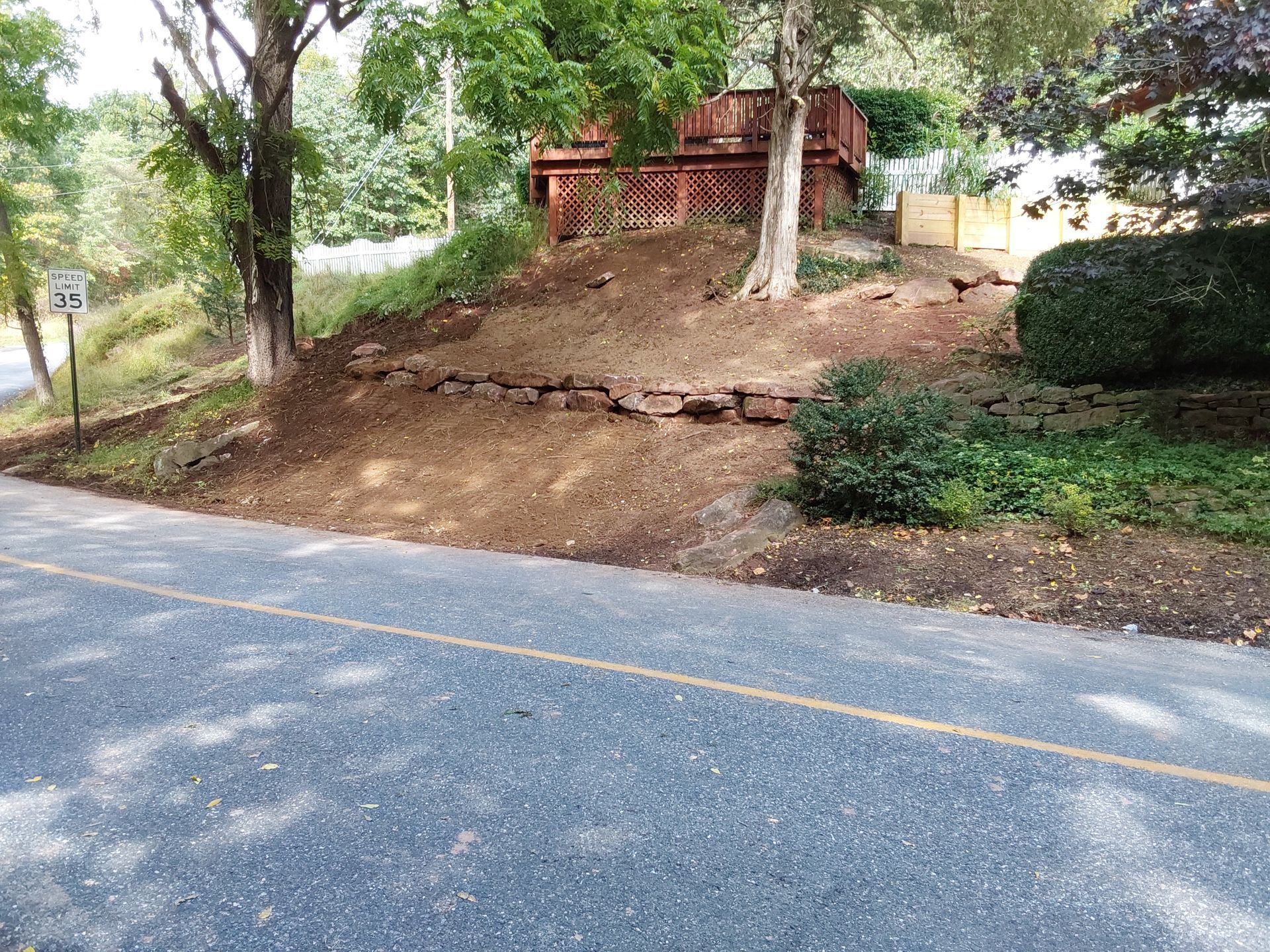 a house is sitting on top of a hill next to a road
